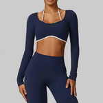 Woman wearing SoftForm™ Long-Sleeve Crop in navy blue long-sleeve athletic top and leggings on a gray background