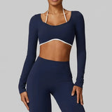 Woman wearing SoftForm™ Long-Sleeve Crop in navy blue long-sleeve athletic top and leggings on a gray background