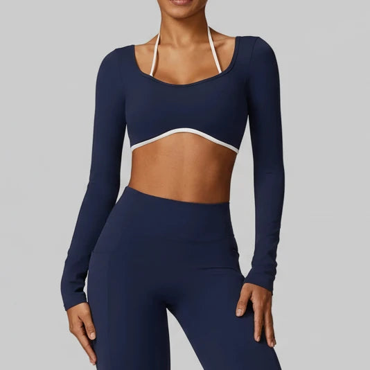 Woman wearing SoftForm™ Long-Sleeve Crop in navy blue long-sleeve athletic top and leggings on a gray background