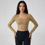 Woman wearing a SoftForm_Long-Sleeve_Yoga_Top_mocha long-sleeve top and black leggings on a gray background