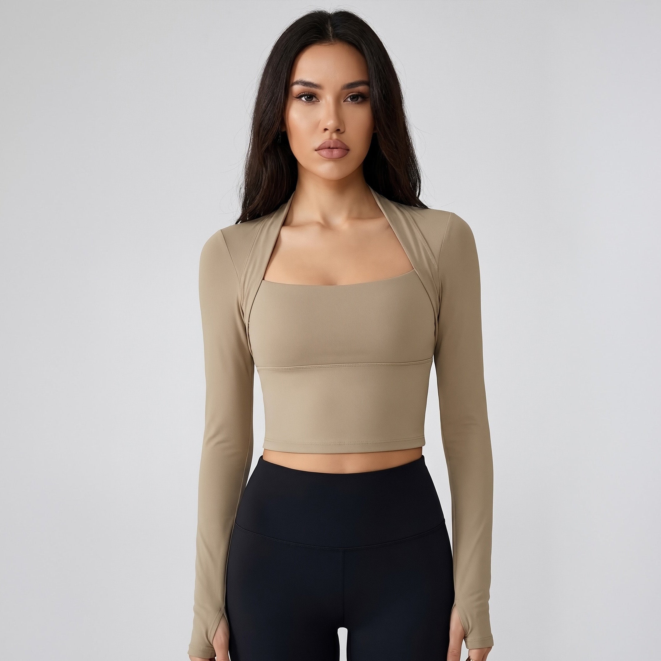Woman wearing a SoftForm_Long-Sleeve_Yoga_Top_taupe long-sleeve top and black leggings on a gray background