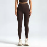 Person wearing brown lSoftForm_Sculpt_Leggings and white sneakers on a light gray background