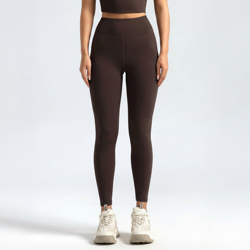 Person wearing brown lSoftForm_Sculpt_Leggings and white sneakers on a light gray background