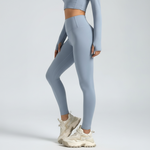 Person wearing light blue leggings and a cropped top on a plain background