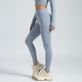 Person wearing light blue leggings and a cropped top on a plain background