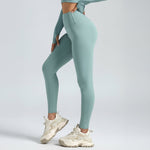 woman wearing teal SoftForm™ Sculpt Leggings and white sneakers on a light gray background
