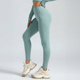 woman wearing teal SoftForm™ Sculpt Leggings and white sneakers on a light gray background