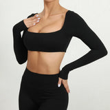 Woman wearing a SoftForm™ Sculpt Tank black long-sleeve crop top and leggings on a white background