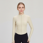 Woman wearing a beige SoftForm™ Slim Jacket  athletic top on a light gray background