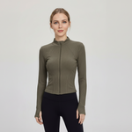 Woman wearing a SoftForm™ Slim Jacket sage green athletic jacket and black leggings on a light gray background