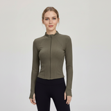 Woman wearing a SoftForm™ Slim Jacket sage green athletic jacket and black leggings on a light gray background