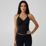 Woman wearing a black halter top and black pants against a plain background