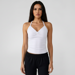 Woman wearing a SoftForm™ Tank in white and black sports pants on a plain background