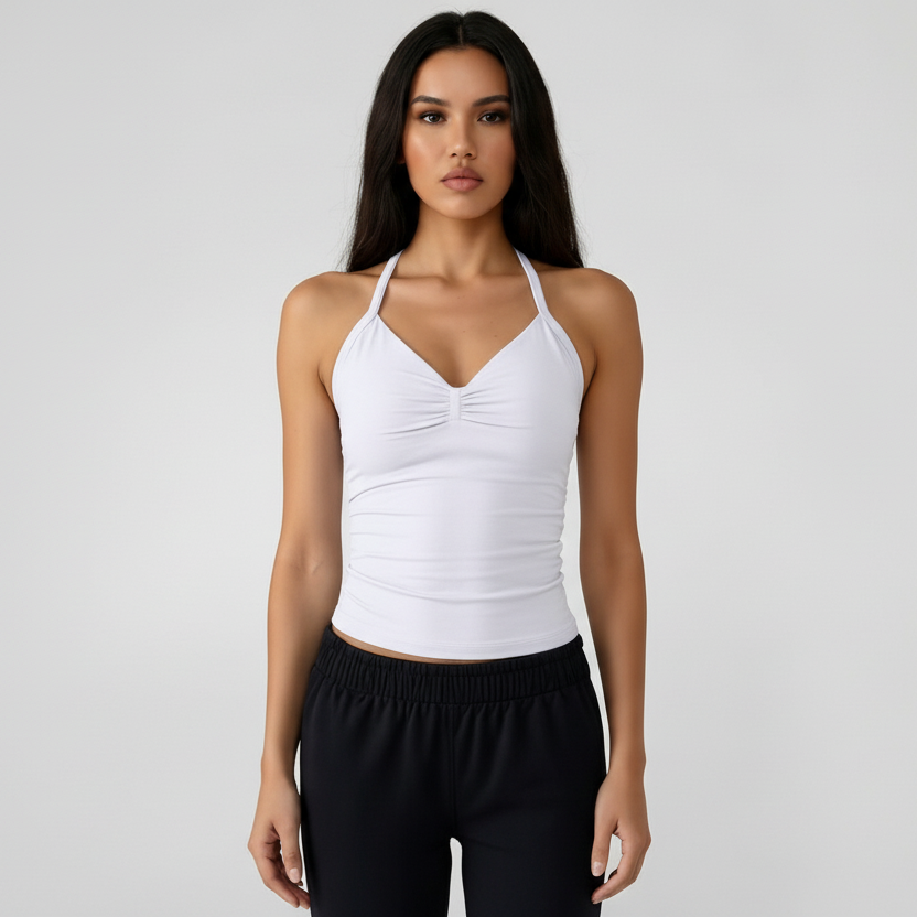 Woman wearing a SoftForm™ Tank in white and black sports pants on a plain background