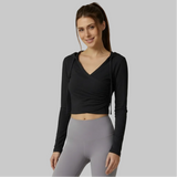 Woman wearing a black long-sleeve top and gray leggings on a gray background