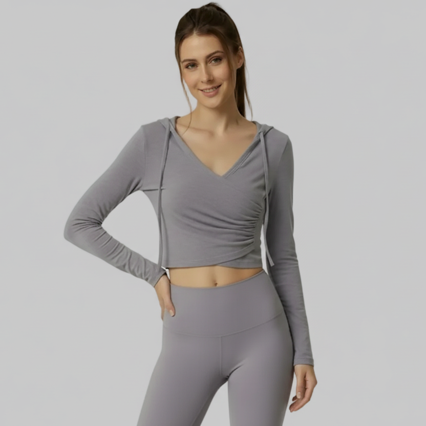 Woman wearing a gray SoftForm™ V-Neck Long-Sleeve Hoodie and leggings on a light gray background
