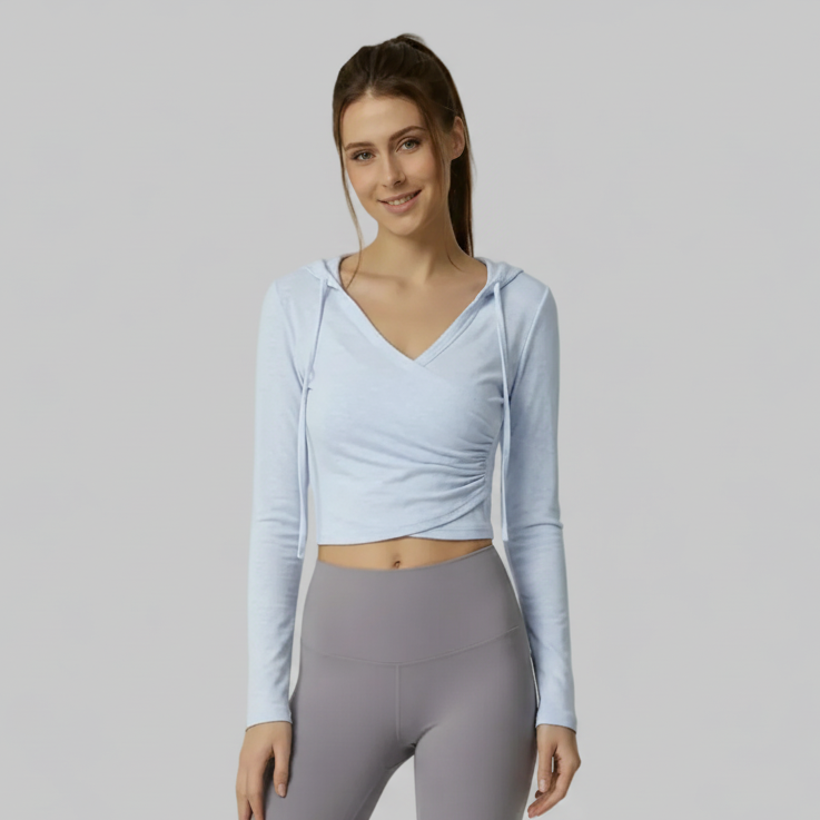 Woman wearing a light blue SoftForm™ V-Neck Long-Sleeve Hoodie and gray leggings on a plain background