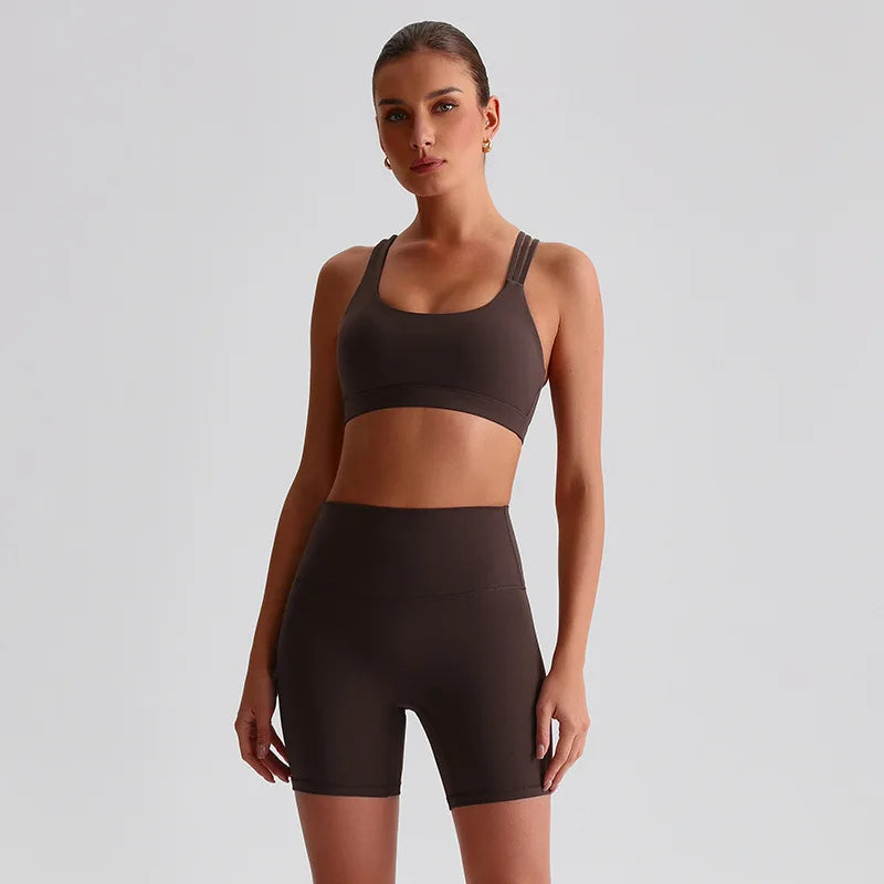Woman wearing a brown SoftForm™ Yoga Set sports bra and shorts in a mocha set on a light gray background
