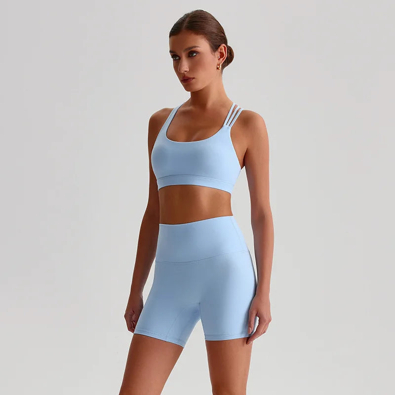 Woman wearing a light blue sports bra and shorts set on a plain background