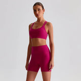 Woman wearing a SoftForm™ Yoga Set_magenta sports bra and shorts set on a light gray background