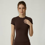 Woman wearing a brown SoftForm_Yoga_Shirt on a plain background