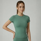 Woman wearing a green SoftForm_Yoga_Shirt on a gray background