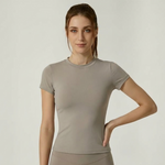 Woman wearing SoftForm_Yoga_Shirt in taupe, with a gray background